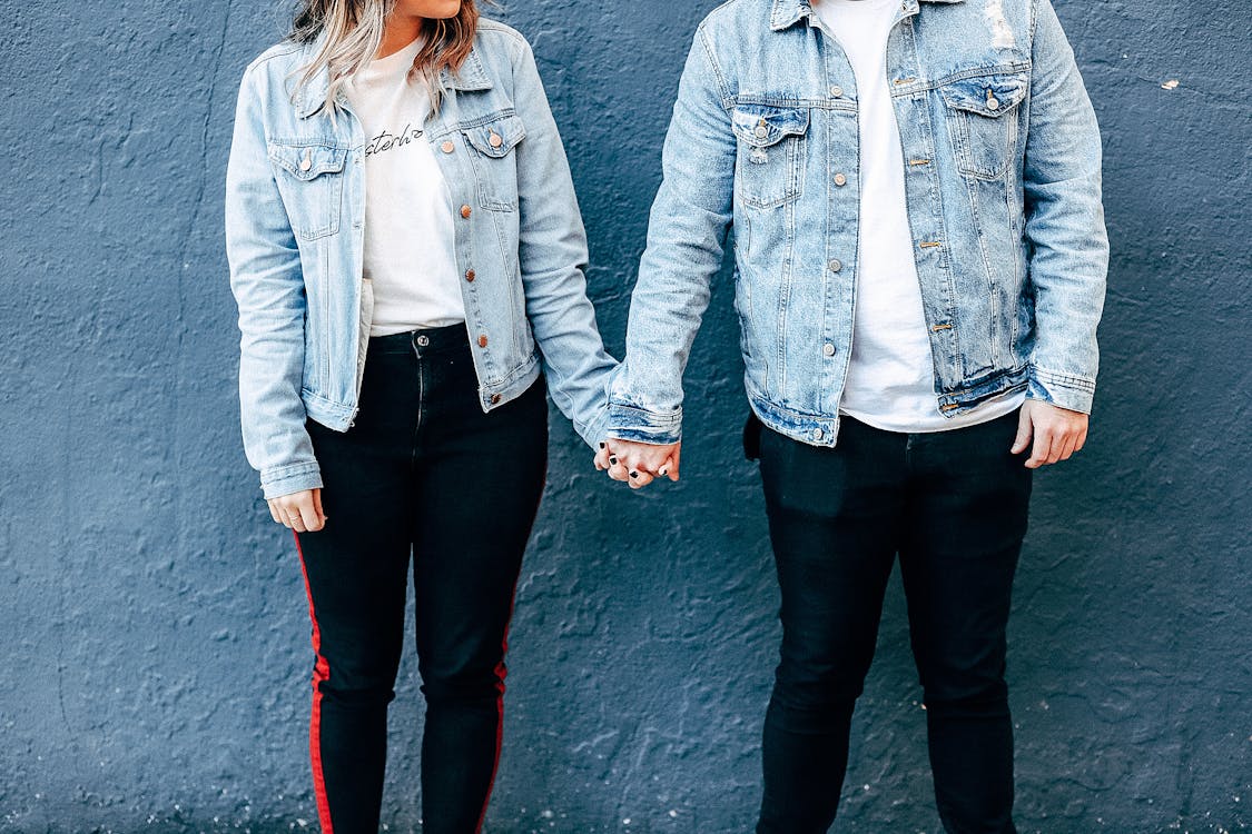 Free Two Person Standing and Holding Their Hands Beside Blue Wall Stock Photo
