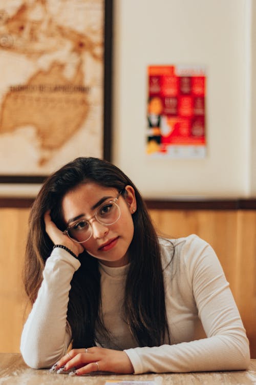 Woman in Eyeglasses Sitting with Hand on Cheek