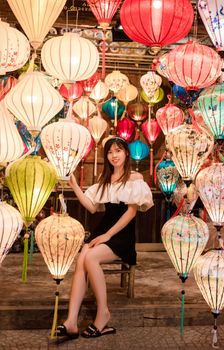 Woman seated amidst vibrant Asian lanterns creating a festive ambiance.