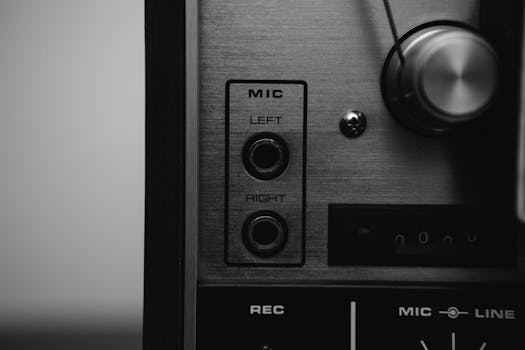 Black and white close-up of a vintage audio mixer with mic inputs, showcasing classic sound technology.