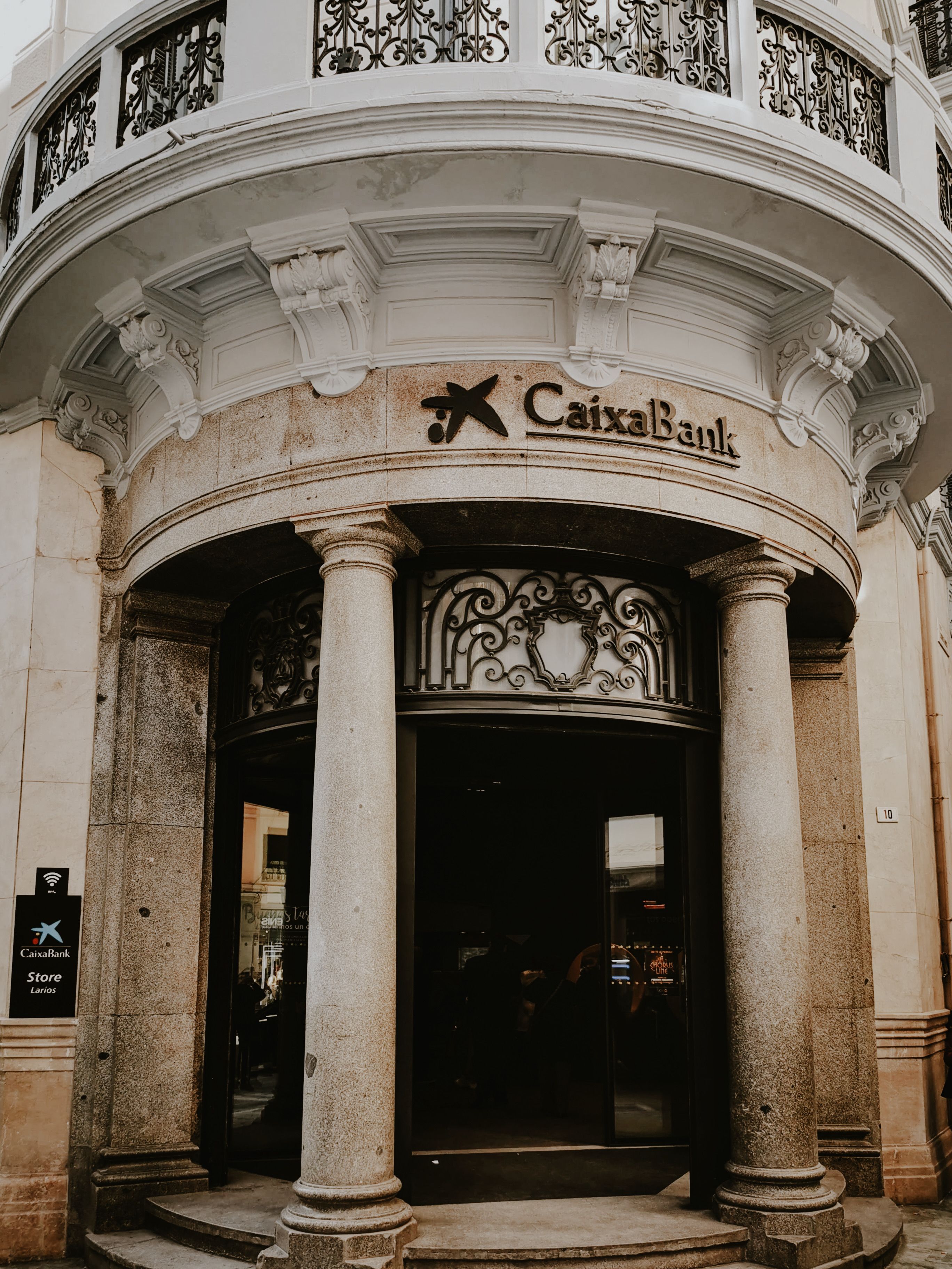 Historic entrance of Caixa Bank with classical columns in urban Spain.