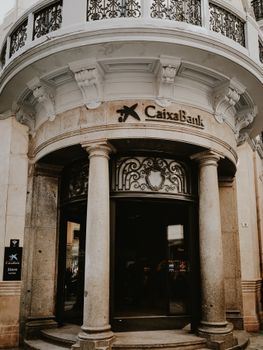 Historic entrance of Caixa Bank with classical columns in urban Spain.