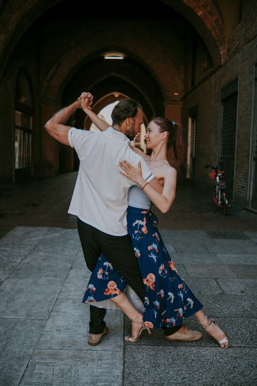 Free A couple gracefully dances under an arched urban passageway, embodying elegance and connection. Stock Photo