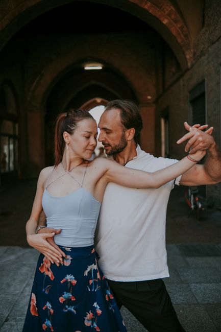 A couple gracefully dances in an urban archway, exuding romance and elegance.