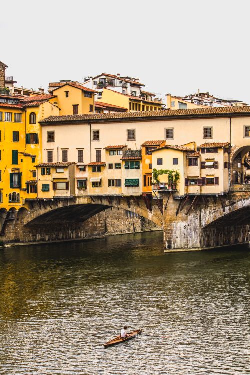 Free Vertical shot of Ponte Vecchio in Florence with a lone canoeist on the Arno River. Stock Photo