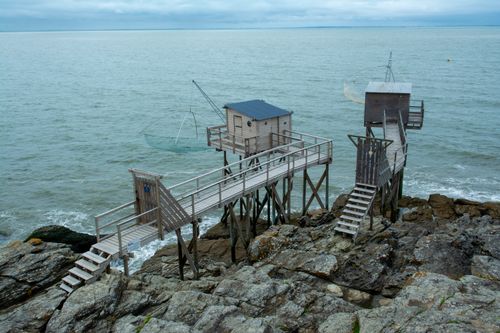 Free Wooden fishing huts on a rocky coast with fishing nets in a serene seaside setting. Stock Photo