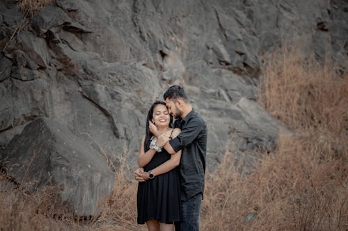 Young Couple Embraces by a Black Rock Cliff