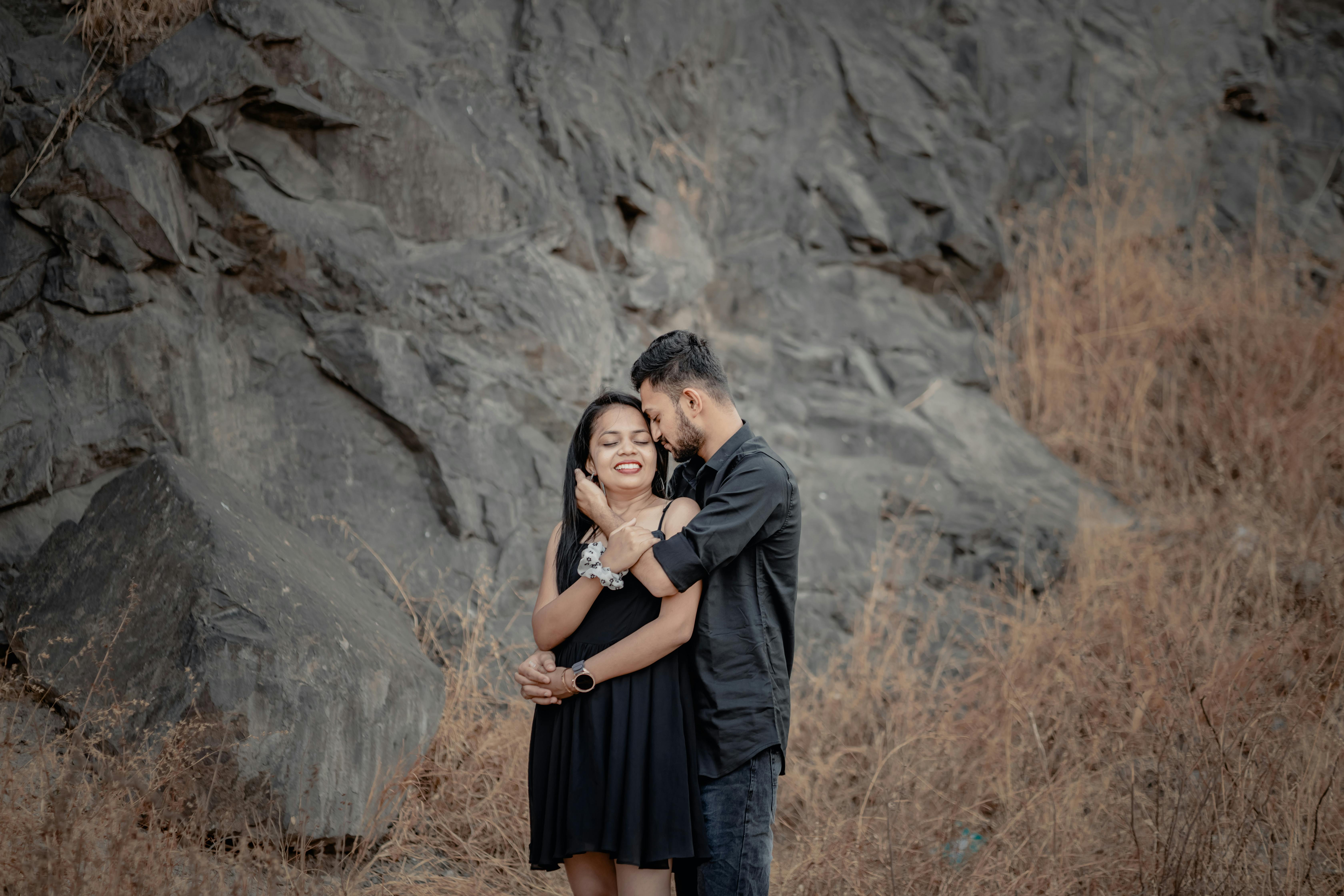 Young Couple Embraces by a Black Rock Cliff · Free Stock Photo