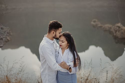 Free Couple embracing by a tranquil lake, captured in a romantic moment outdoors. Stock Photo