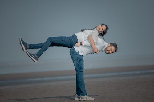 Free A joyful couple enjoys playful moments on a serene beachfront. Perfect for lifestyle themes. Stock Photo