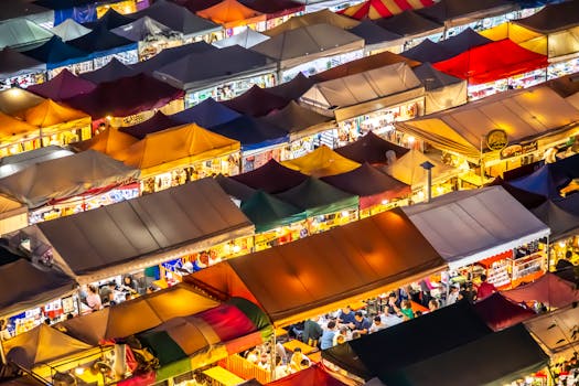 Colorful tents and bustling crowds at Bangkok's vibrant night market seen from above.