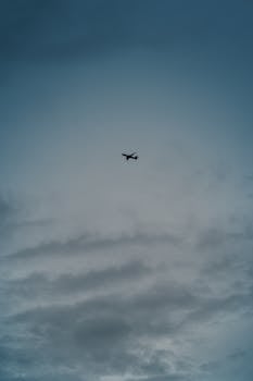 A solitary airplane flying through a dramatic cloudy sky, captured from below.