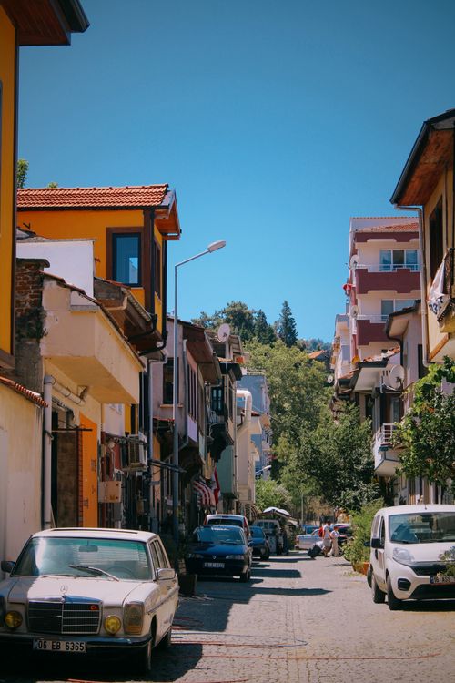 Free A scenic street view with colorful buildings and vintage cars under a bright blue sky. Stock Photo