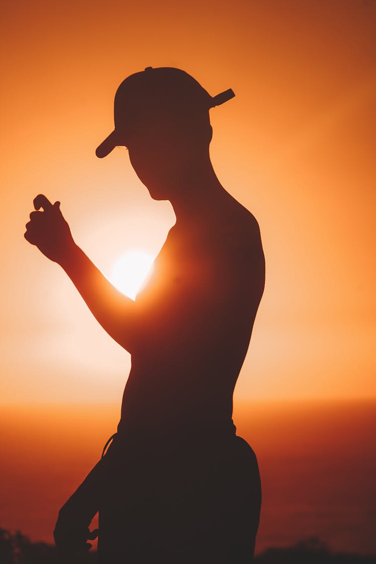 Silhouette Of Man In Hat At Sunset