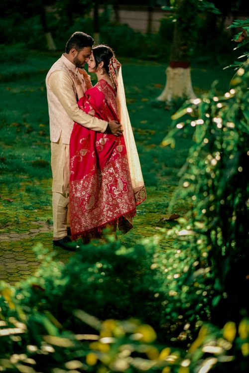 Free A newlywed couple in traditional attire embraces in a lush outdoor setting. Stock Photo