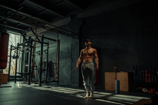 A muscular man poses confidently in a dimly lit gym, highlighting his toned physique.