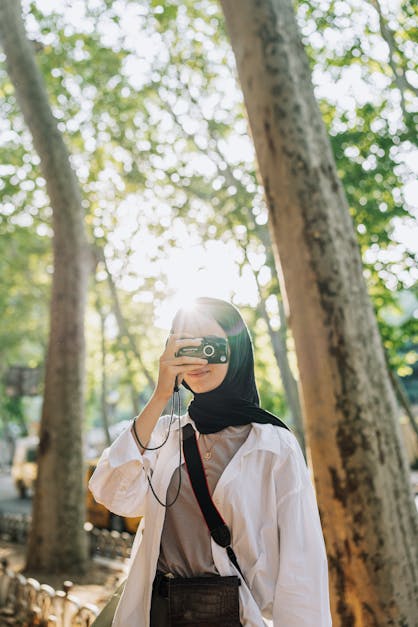 Cute hijab girl with camera and peace sign female photographer