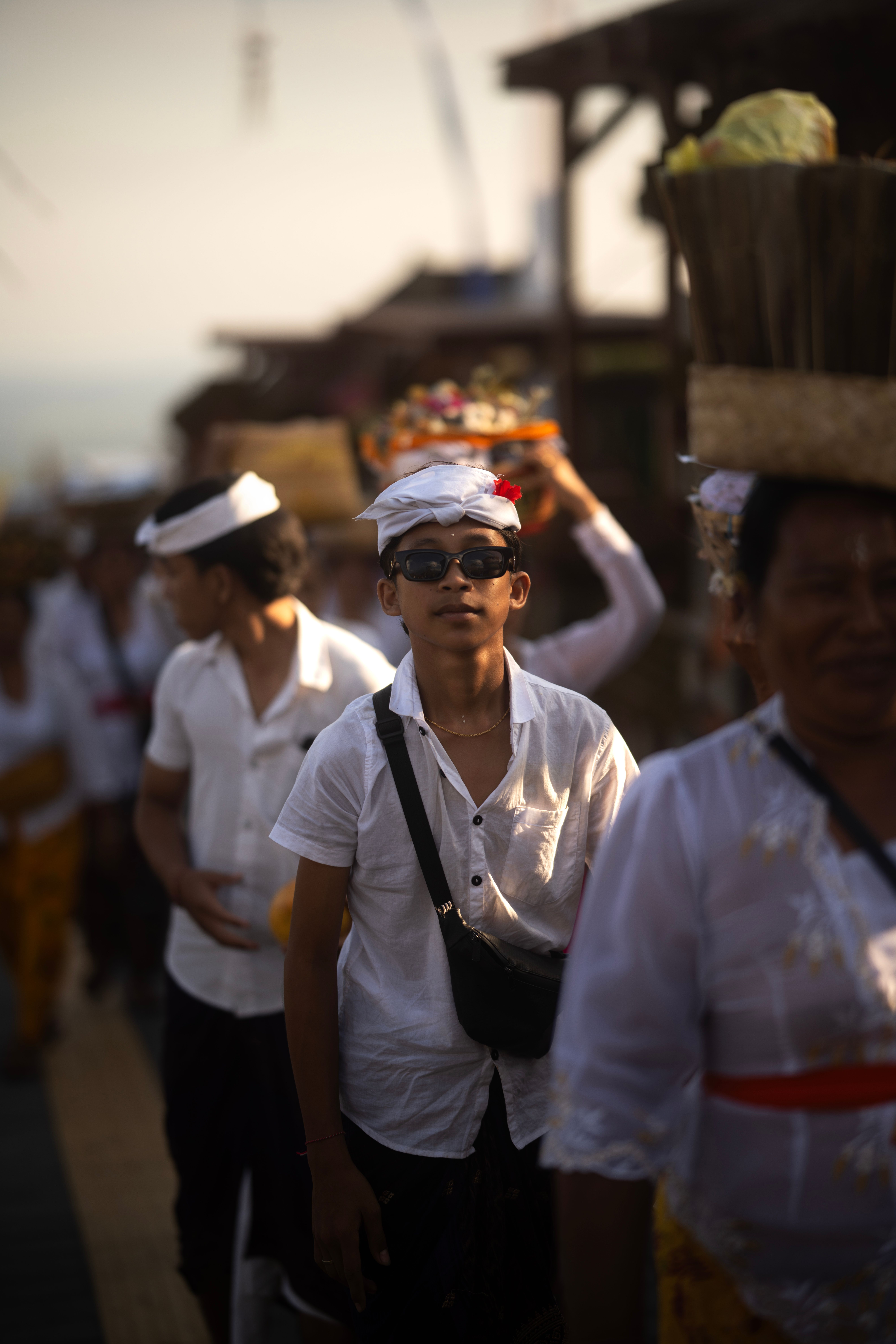 Young participants in a vibrant traditional ceremony wearing white shirts and carrying offerings.