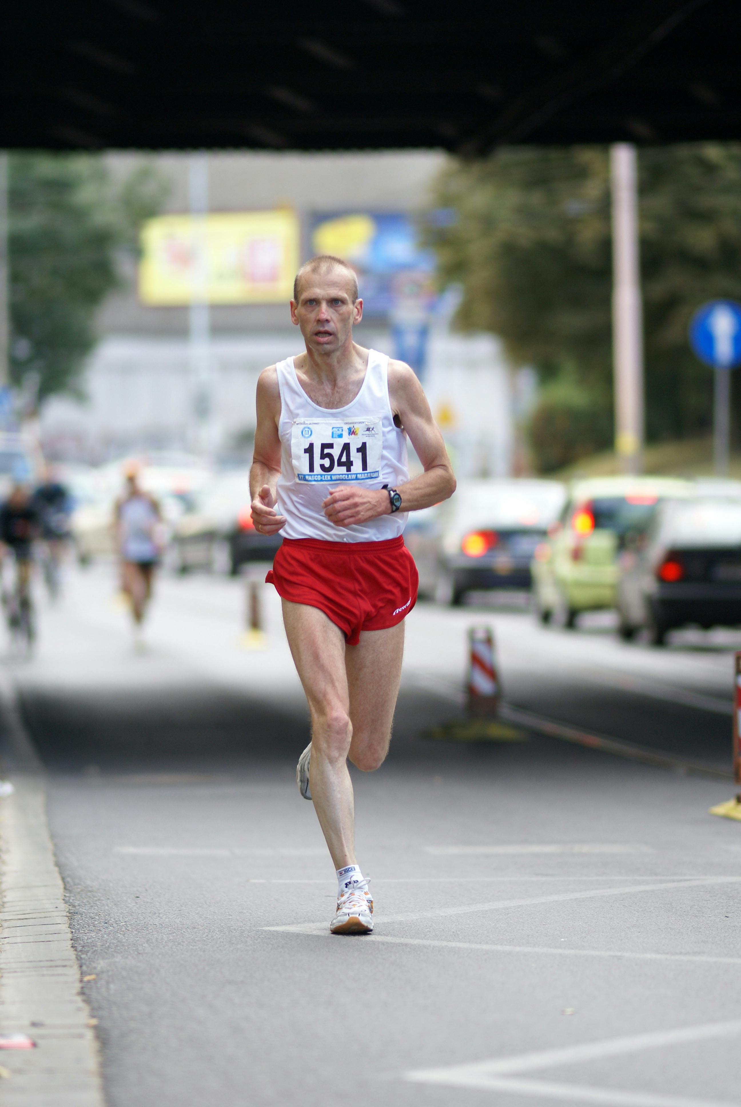 Focused male runner in a marathon on a city street in Wrocław, Poland.