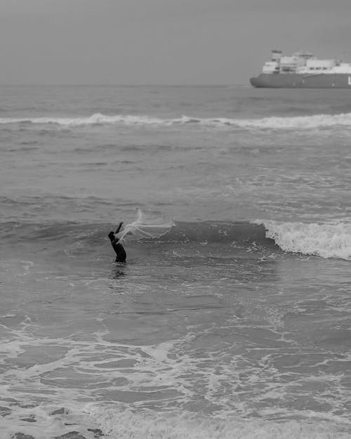 Waves near Person Standing in Sea in Black and White