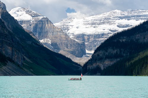 People in Boat with Flag of Canada among Majestic Mountains