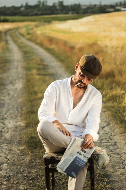 Foto profissional grátis de cadeira, camisa branca, cigarro