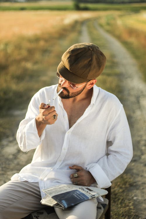 Foto profissional grátis de cadeira, camisa branca, cigarro