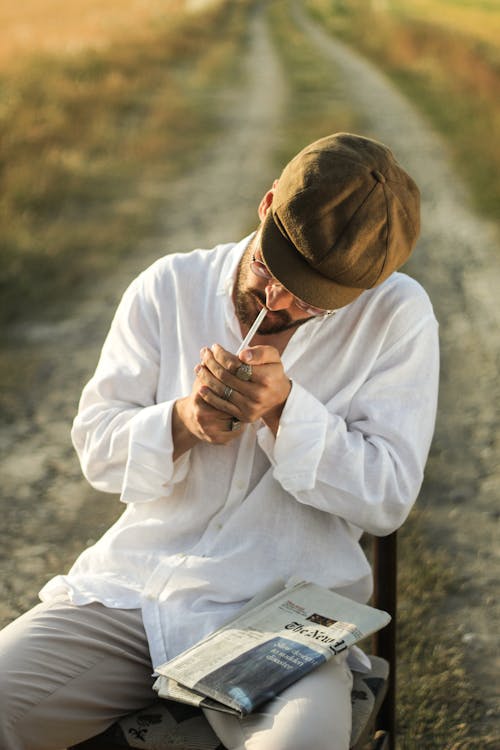 Foto profissional grátis de cadeira, camisa branca, cigarro