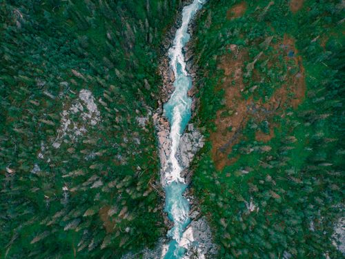 Free Stunning aerial view of turquoise river cutting through lush green forest, showcasing natural beauty. Stock Photo