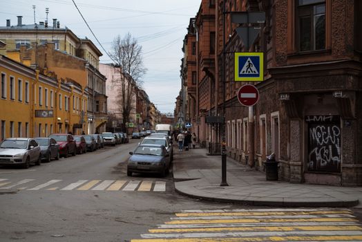 A city street view with historical buildings, cars, and pedestrian signage