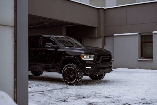 A sleek black pickup truck parked on snowy city streets in winter, showcasing a modern urban vibe.