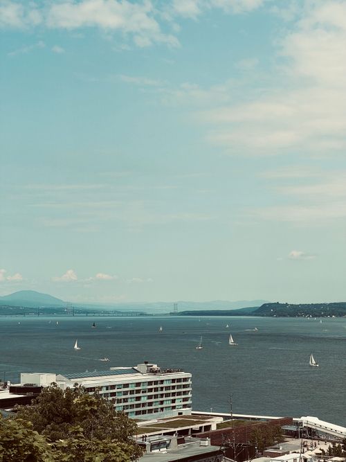 Free Scenic view of sailboats on a lake with modern buildings and distant hills under a clear sky. Stock Photo