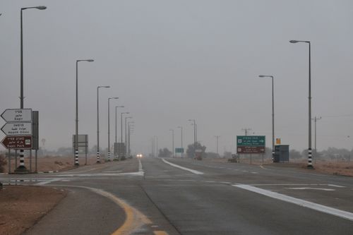 Free Foggy desert road with traffic signs and lamp posts, conveying a moody atmosphere. Stock Photo