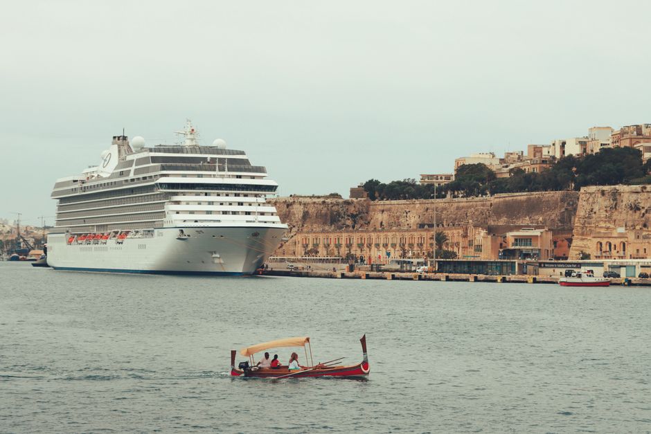 A luxury cruise ship moored in the scenic Valletta harbor with historic buildings in the background, Malta.