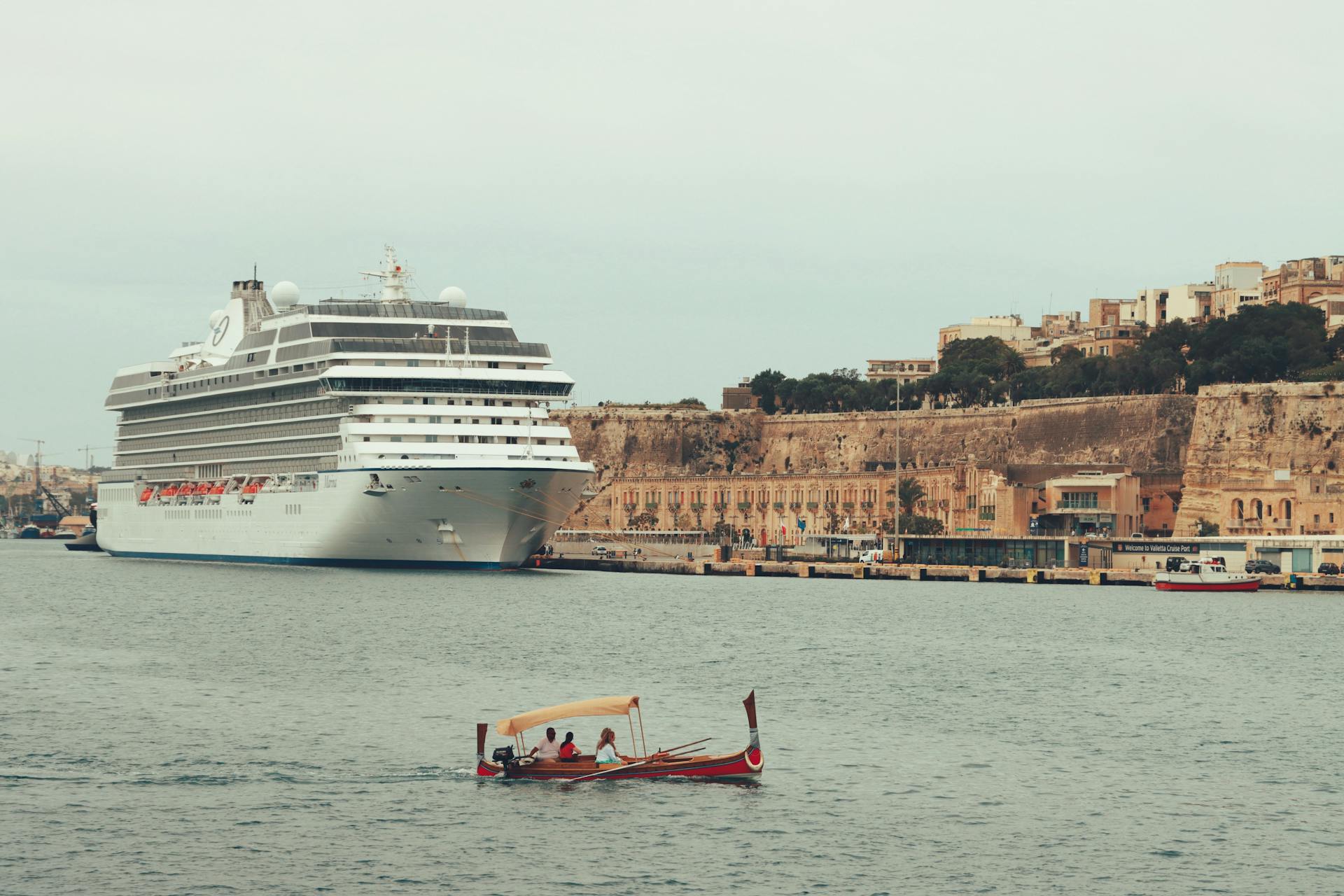 A luxury cruise ship moored in the scenic Valletta harbor with historic buildings in the background, Malta.