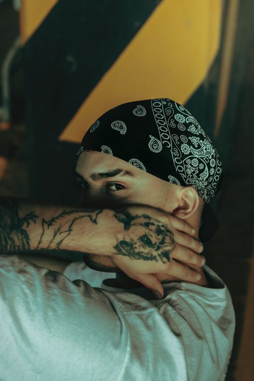 Free Captivating portrait of a tattooed man with a patterned bandana, indoors, in expressive light. Stock Photo