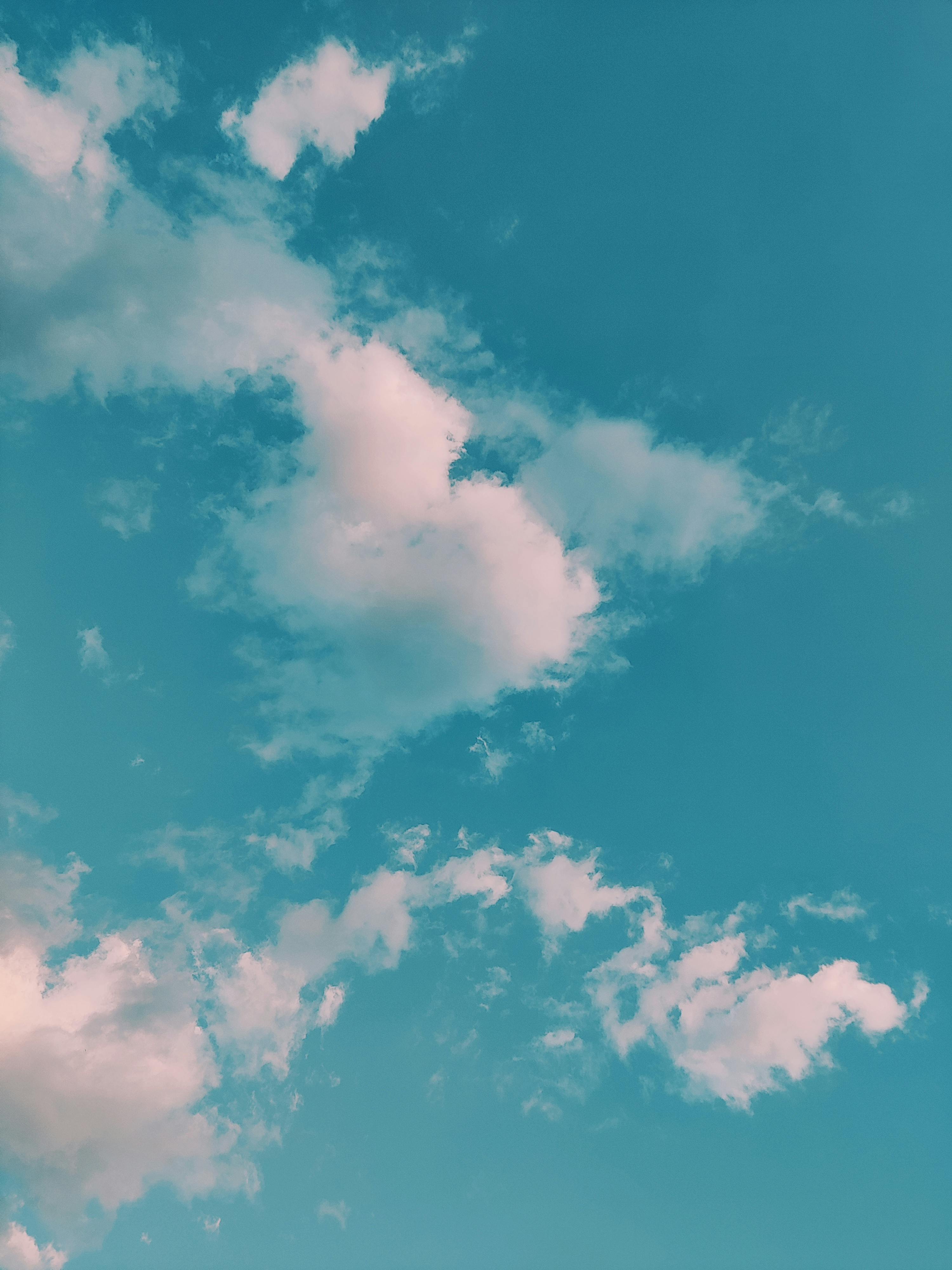 A tranquil view of a clear blue sky dotted with soft, fluffy clouds. Perfect for nature backgrounds.