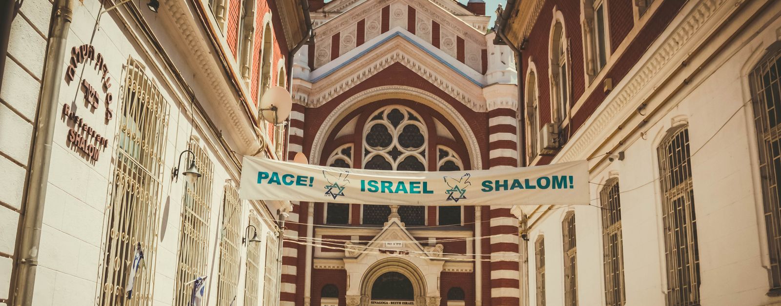 Gothic Revival architecture of Brașov Synagogue with a peace message banner under daylight.