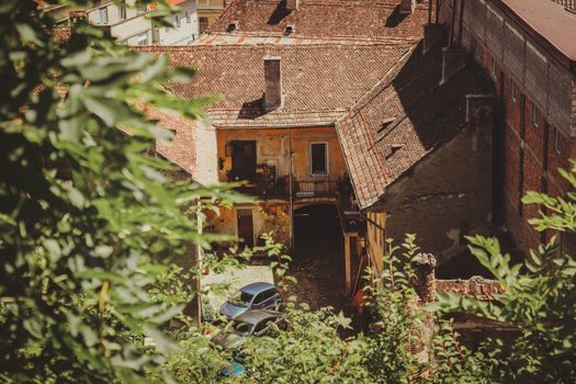 A picturesque view of a charming old courtyard in Brașov, Romania, bathed in summer sunlight.