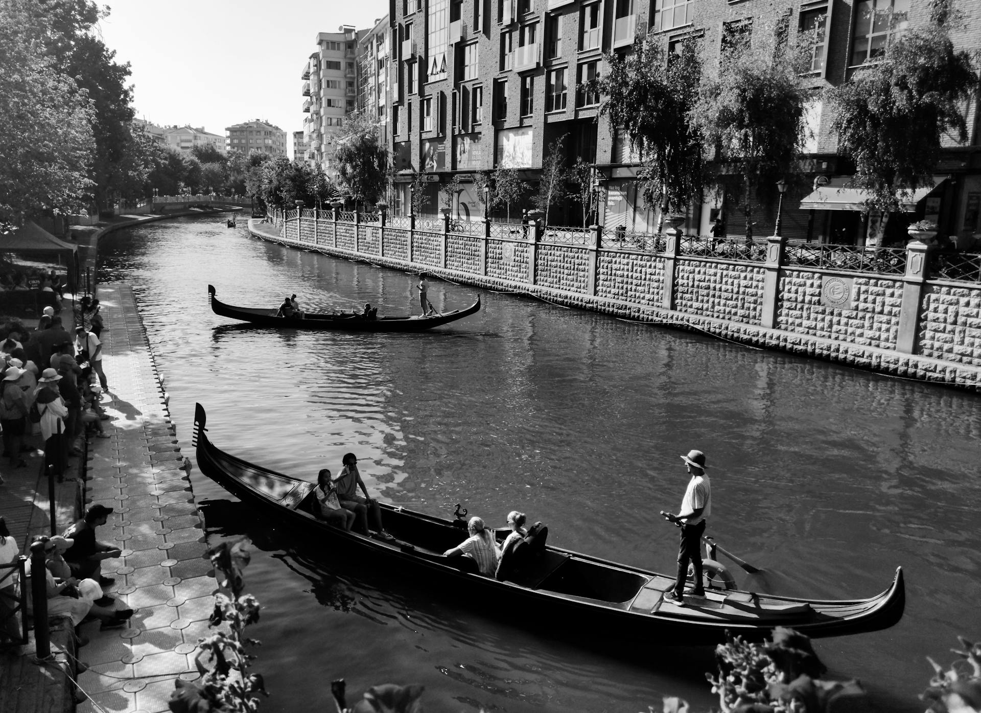 Black and white photo of gondolas navigating a canal in Eskişehir, Türkiye.