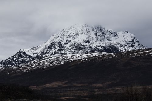 Free A majestic snow-capped mountain stands tall under a cloudy sky, capturing the essence of winter. Stock Photo