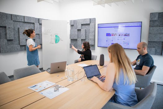 A group of professionals engaged in a team meeting with a presentation in a modern office setting.