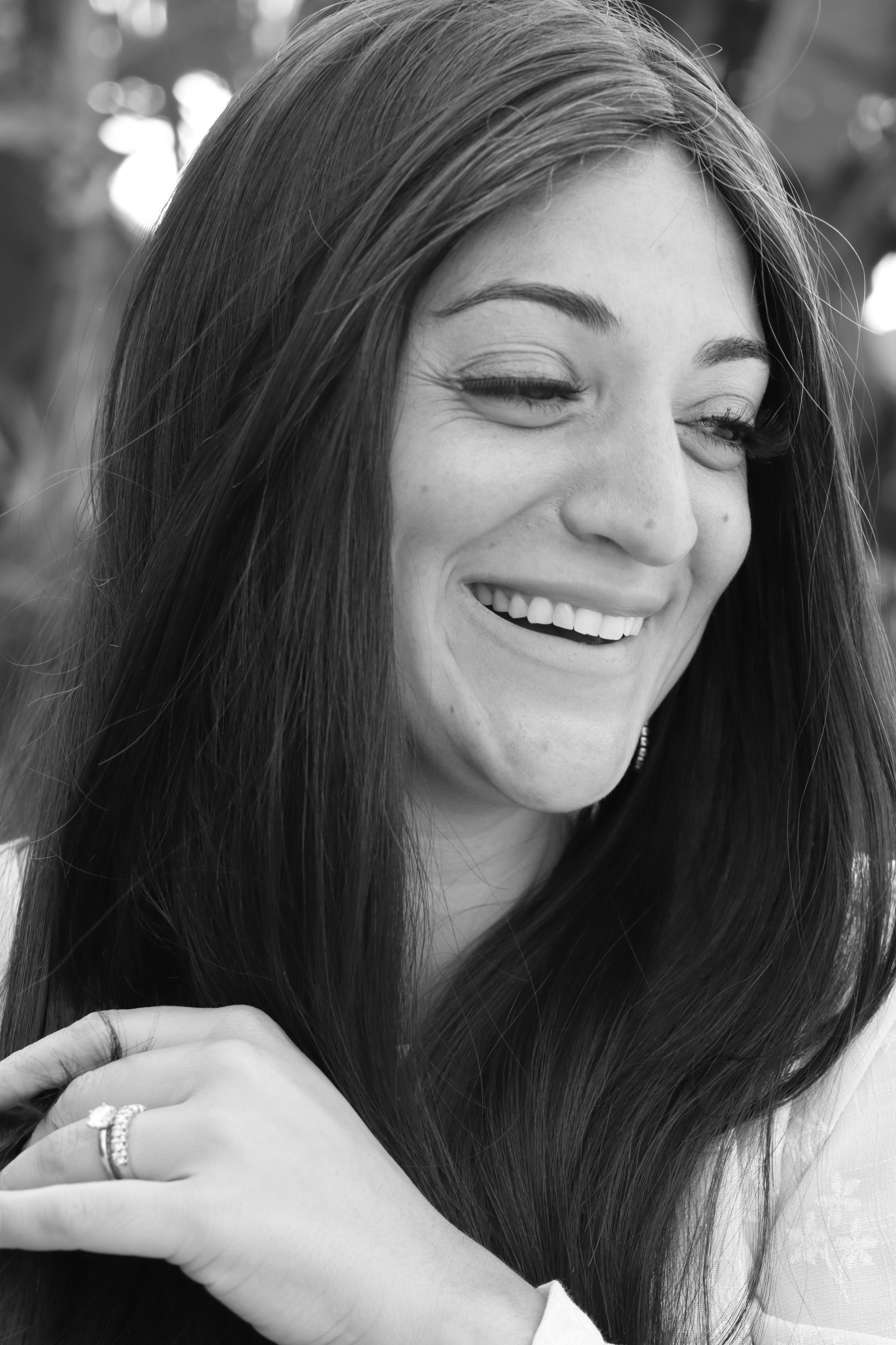 A natural and candid black and white portrait of a smiling woman with long hair.