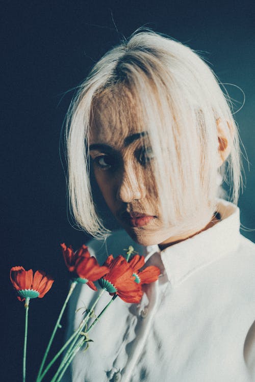 A woman with blonde hair holding red flowers