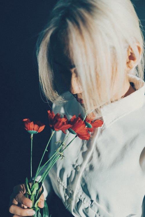 A woman with blonde hair holding red flowers