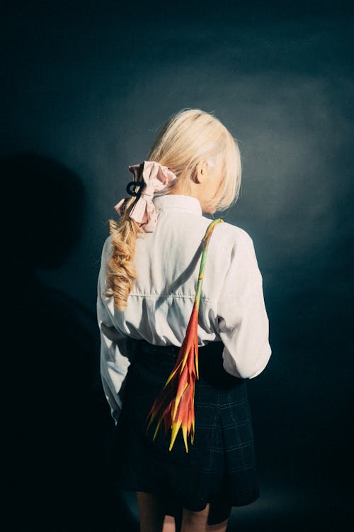 A woman with long blonde hair and a feather bag