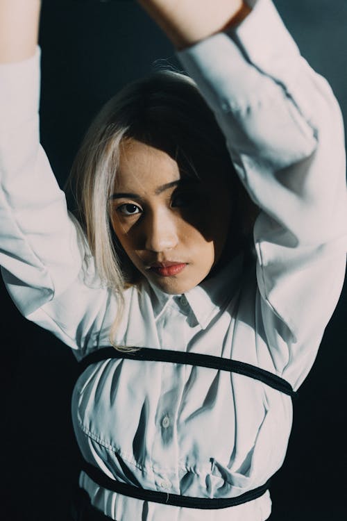 A woman in white shirt and black tie holding a rope