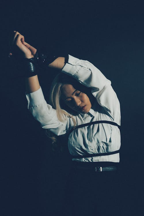 A woman in a white shirt and black tie is holding her arms up