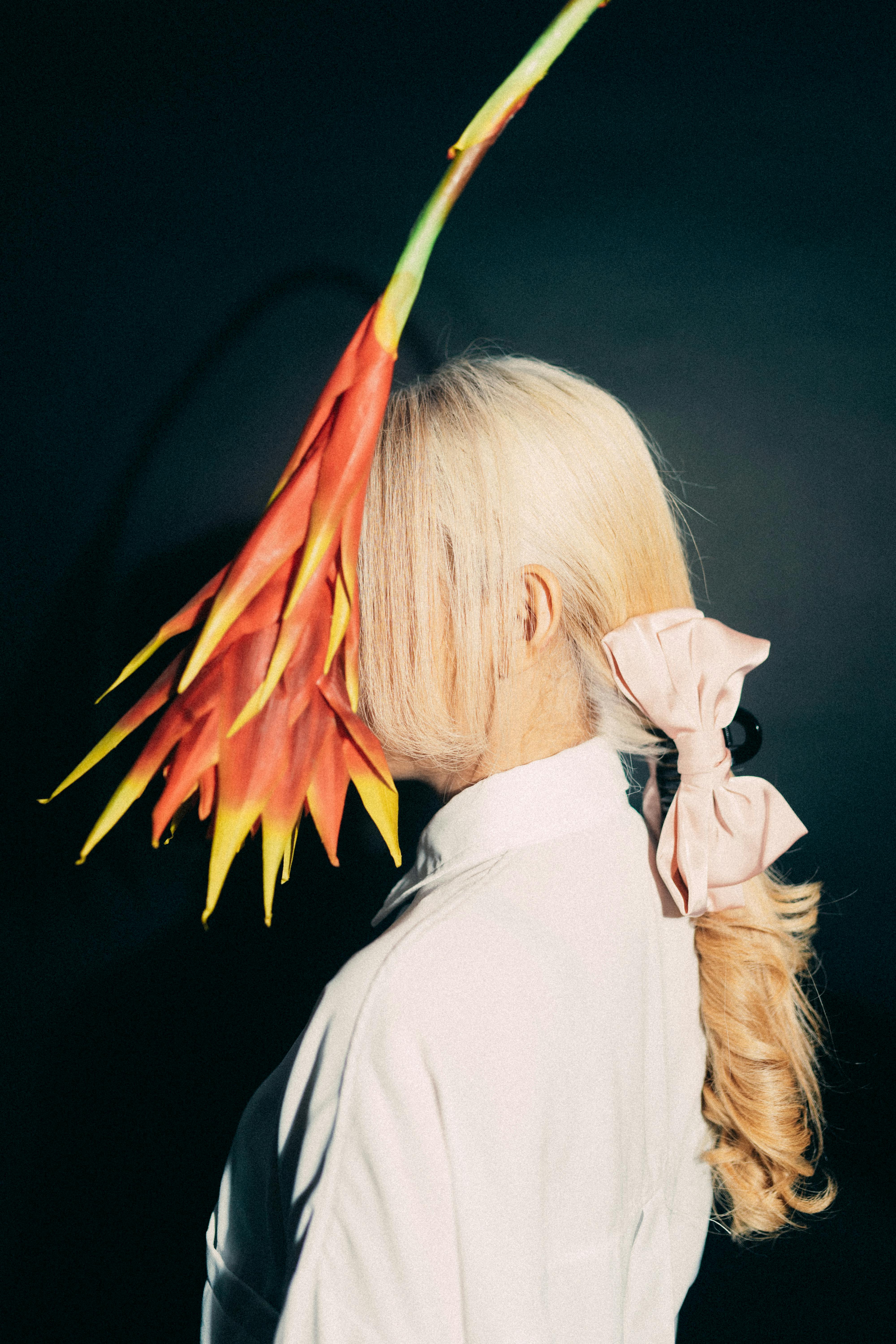 Artistic portrait of a woman wearing a large flower hat, mixing fashion and nature in a creative style.