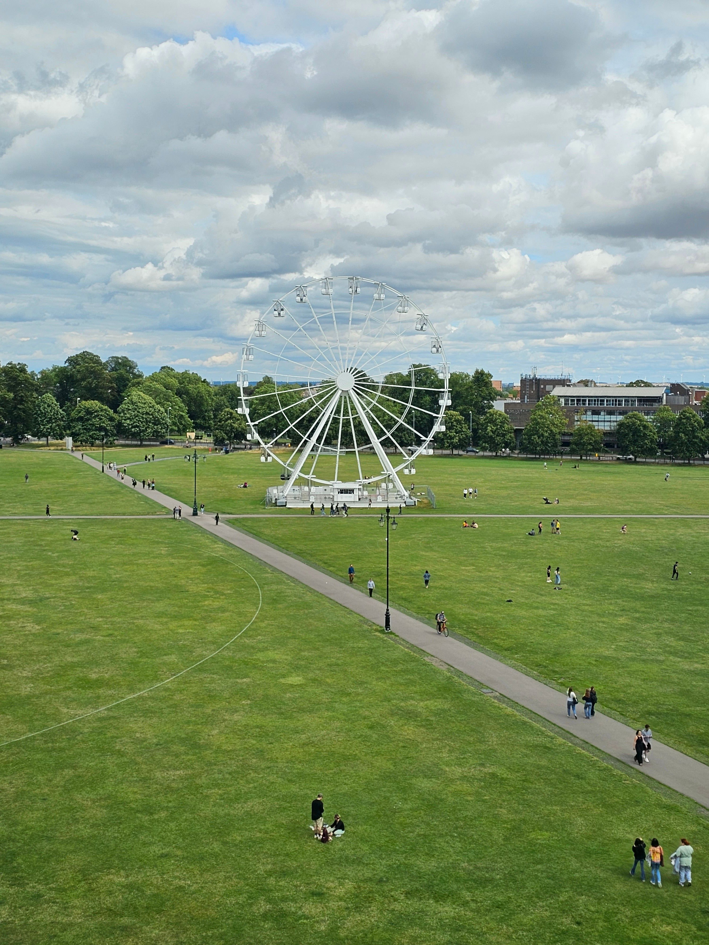 A sunny day at Parker's Piece in Cambridge featuring a Ferris wheel and leisure activities.